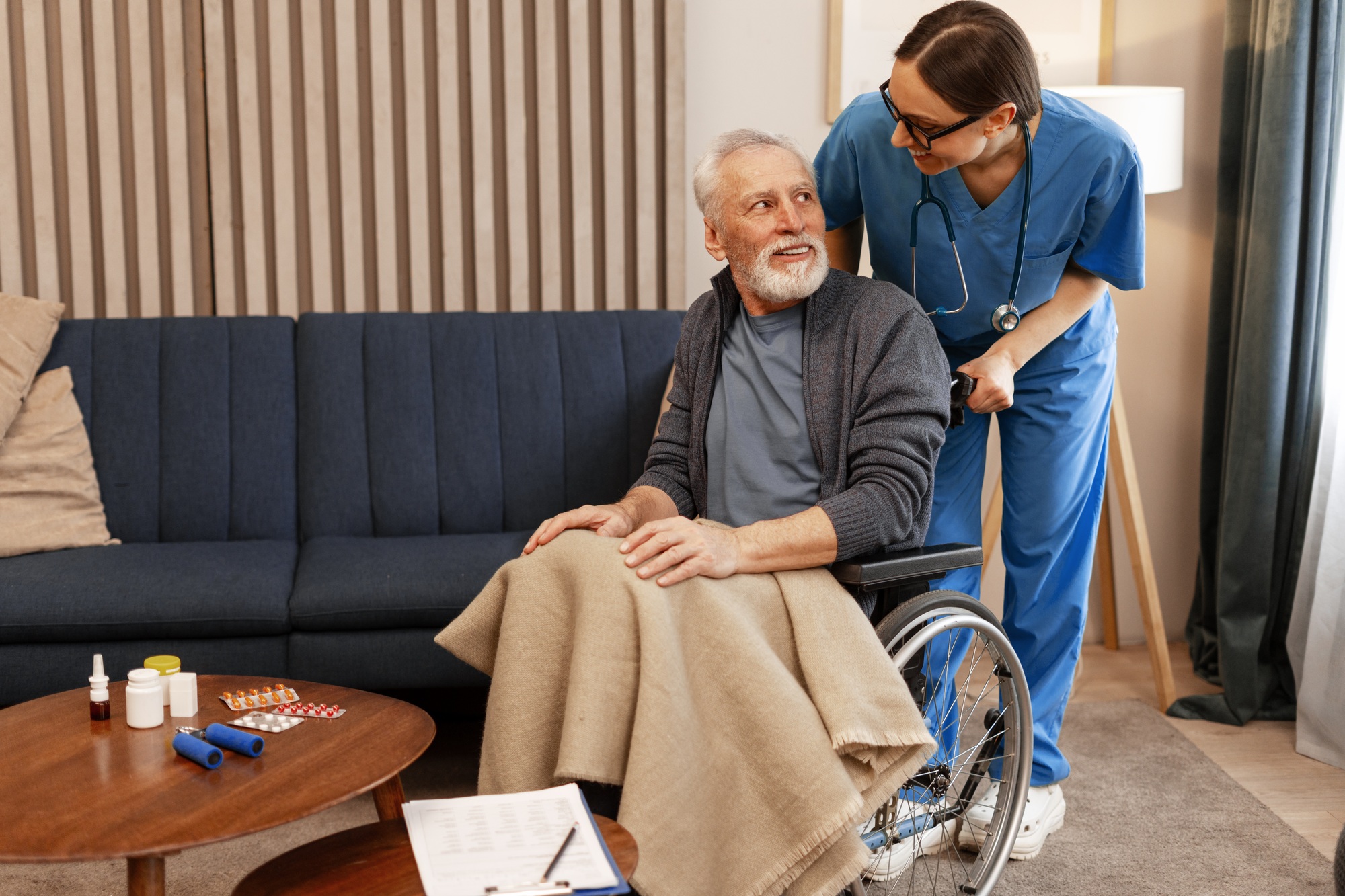 Nurse assisting elderly man in wheelchair at home