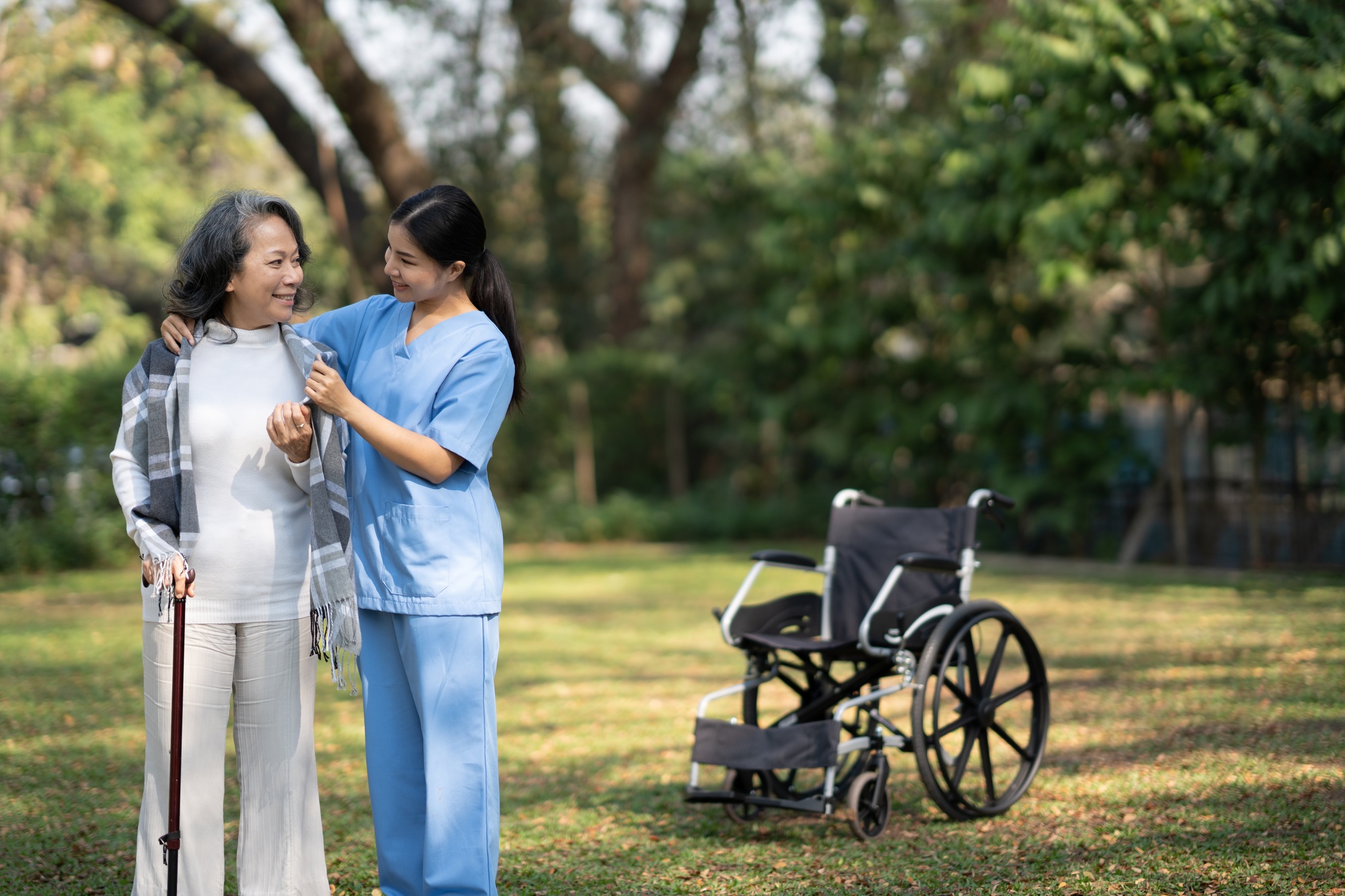 Old lady smiling at her nurse while the nurse is taking care of her. Professional nurse assistant